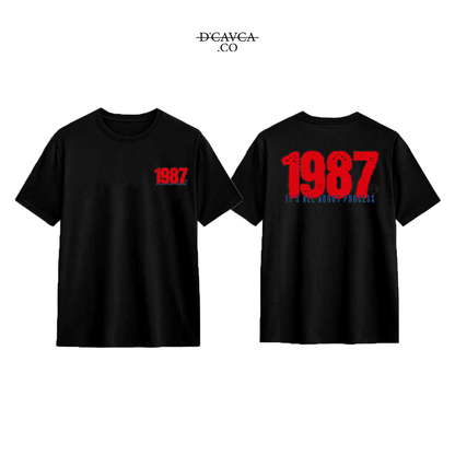 Black t-shirt with '1987' printed on the front and back, featuring the brand 'DCAVCA'.
